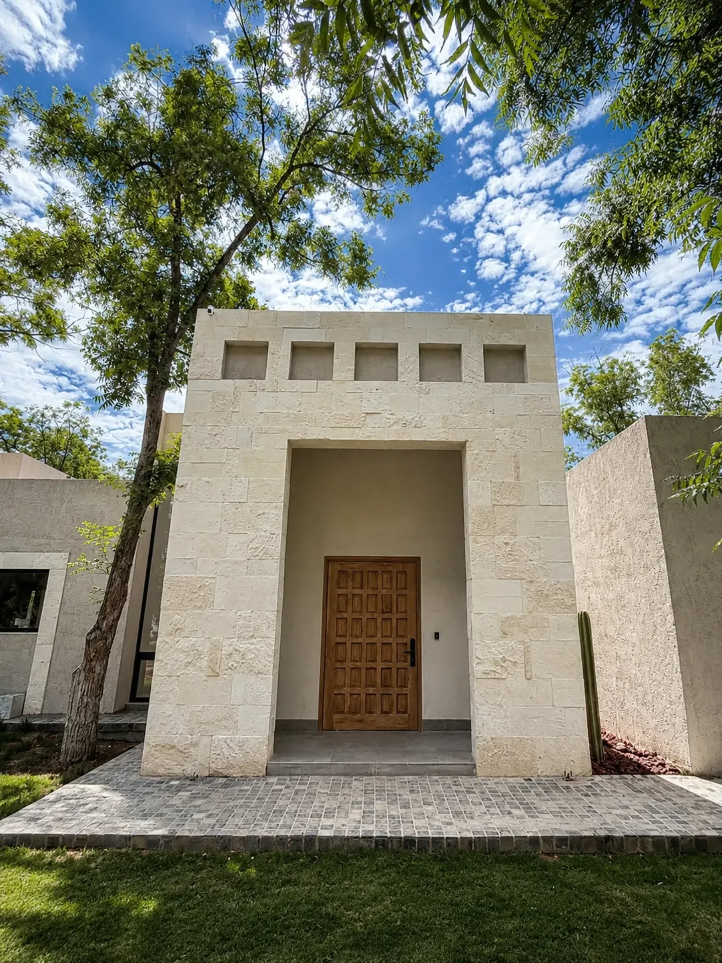 Acceso principal de Finca Los Nogales: portada de piedra clara y puerta de madera entre nogales
